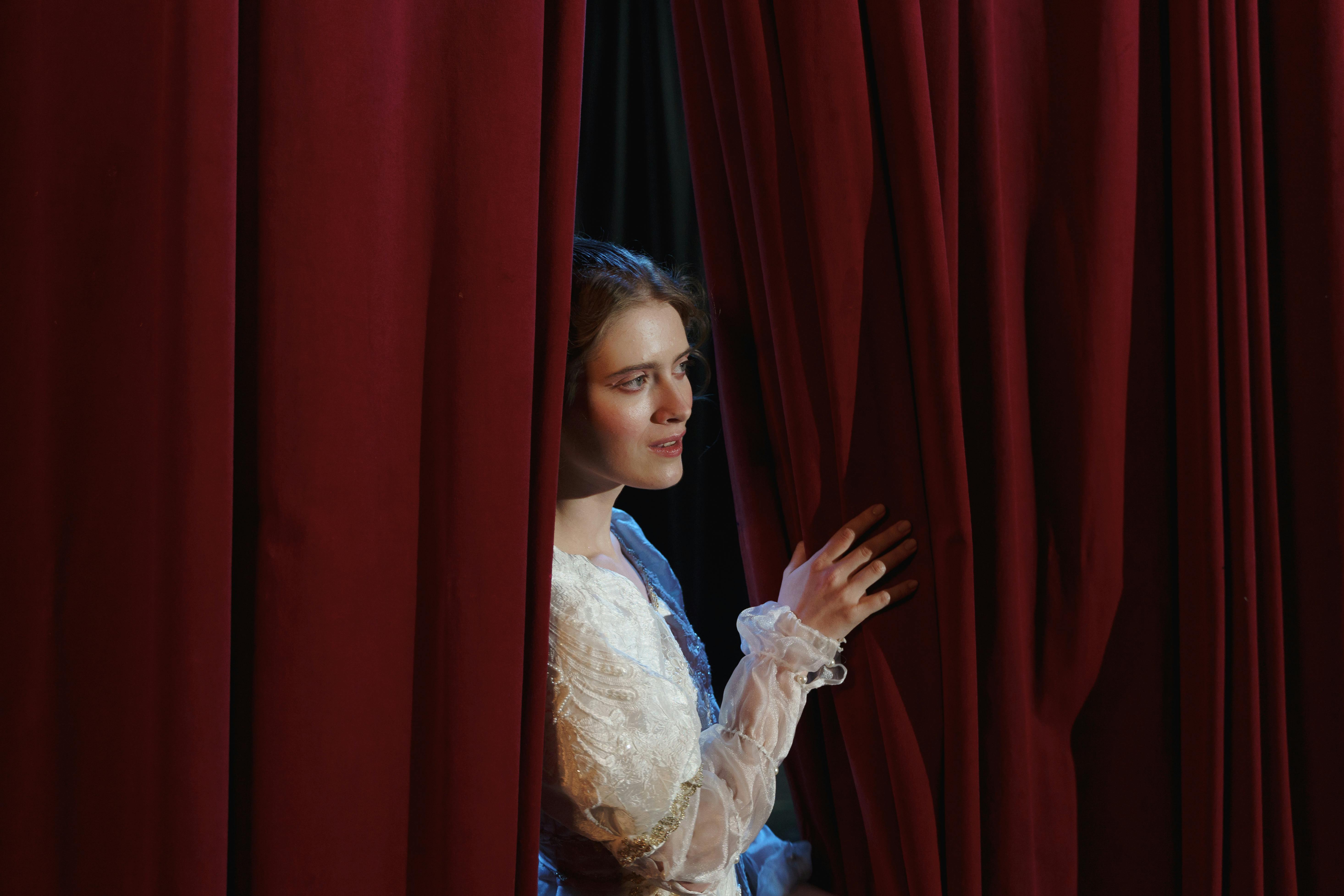 Woman looking behind the curtains.
